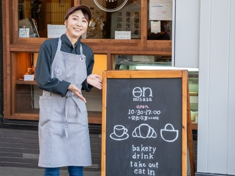 黒板を指すエプロン姿の女性