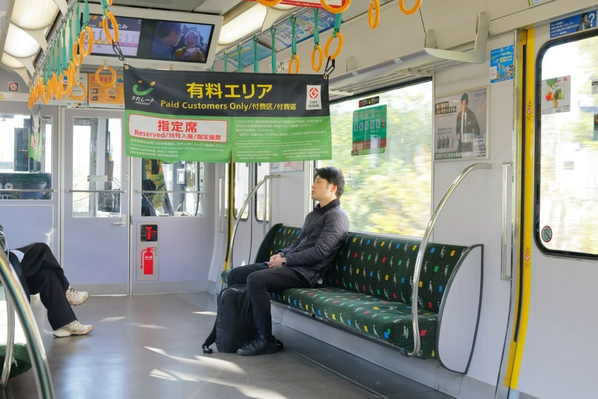 電車のロングシートに一人座っている