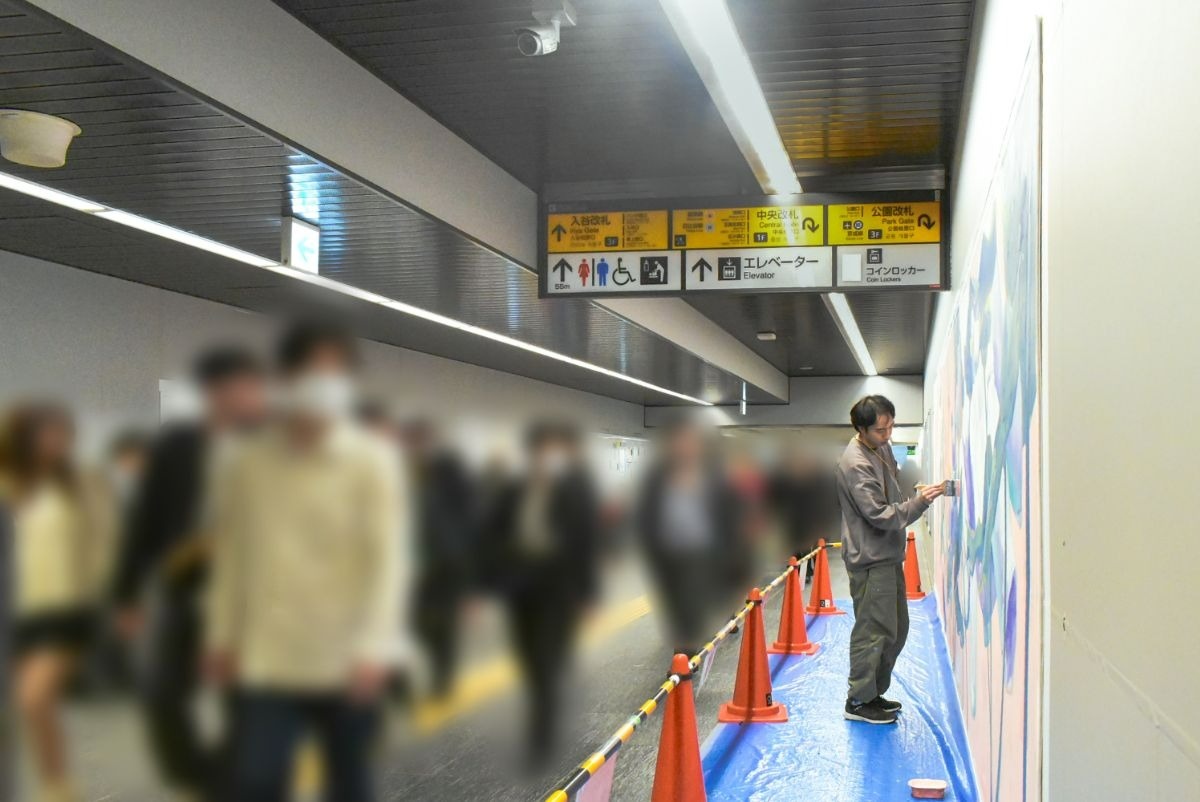 ボカシの入った人と壁の前に立つ男性