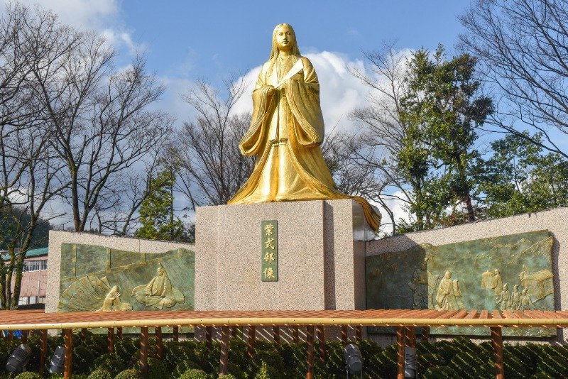 十二単をまとった紫式部像。台座のレリーフも要注目