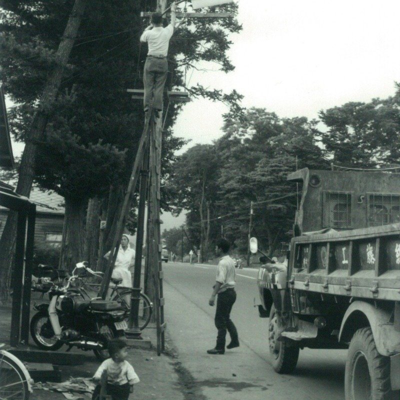 沿道を照らす街灯を直している1960年代の様子