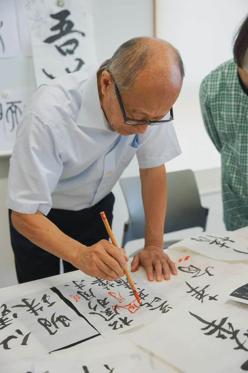 生徒さんの字を朱墨で添削する若松さん