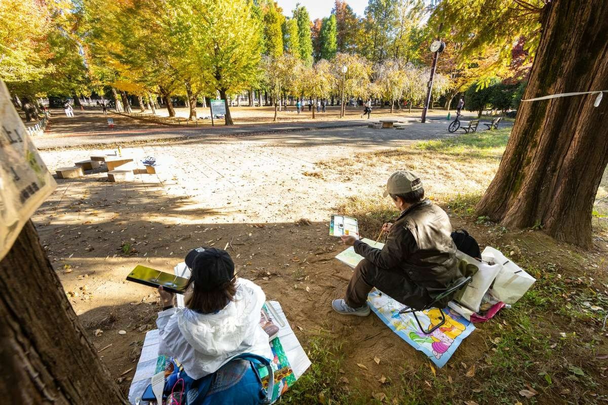 黄葉の道をスケッチするおおやまさん（右）