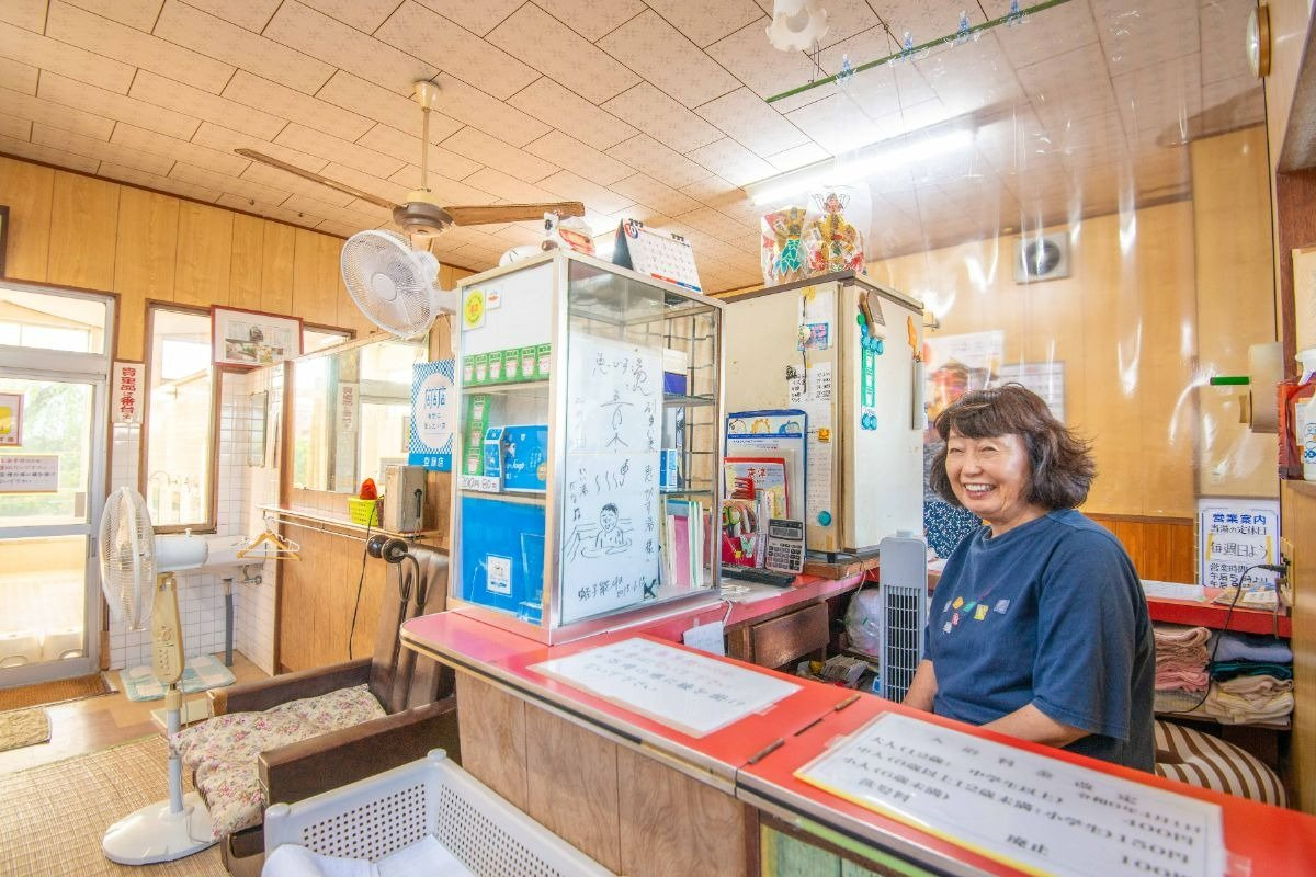 笑顔で番台に座るオーナーの島﨑羊子さん