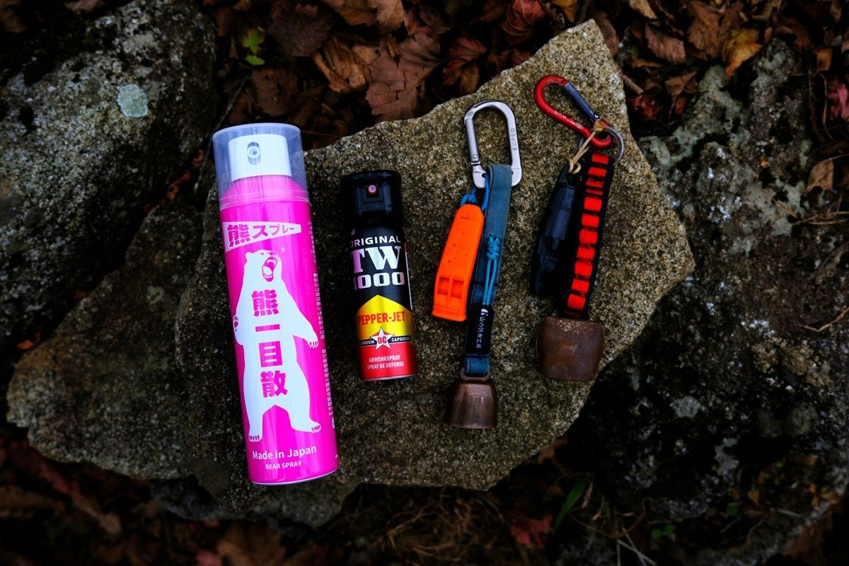 左から国内メーカーの熊スプレー、ドイツ製の熊スプレー、熊鈴とホイッスルはセットで持ち歩く
