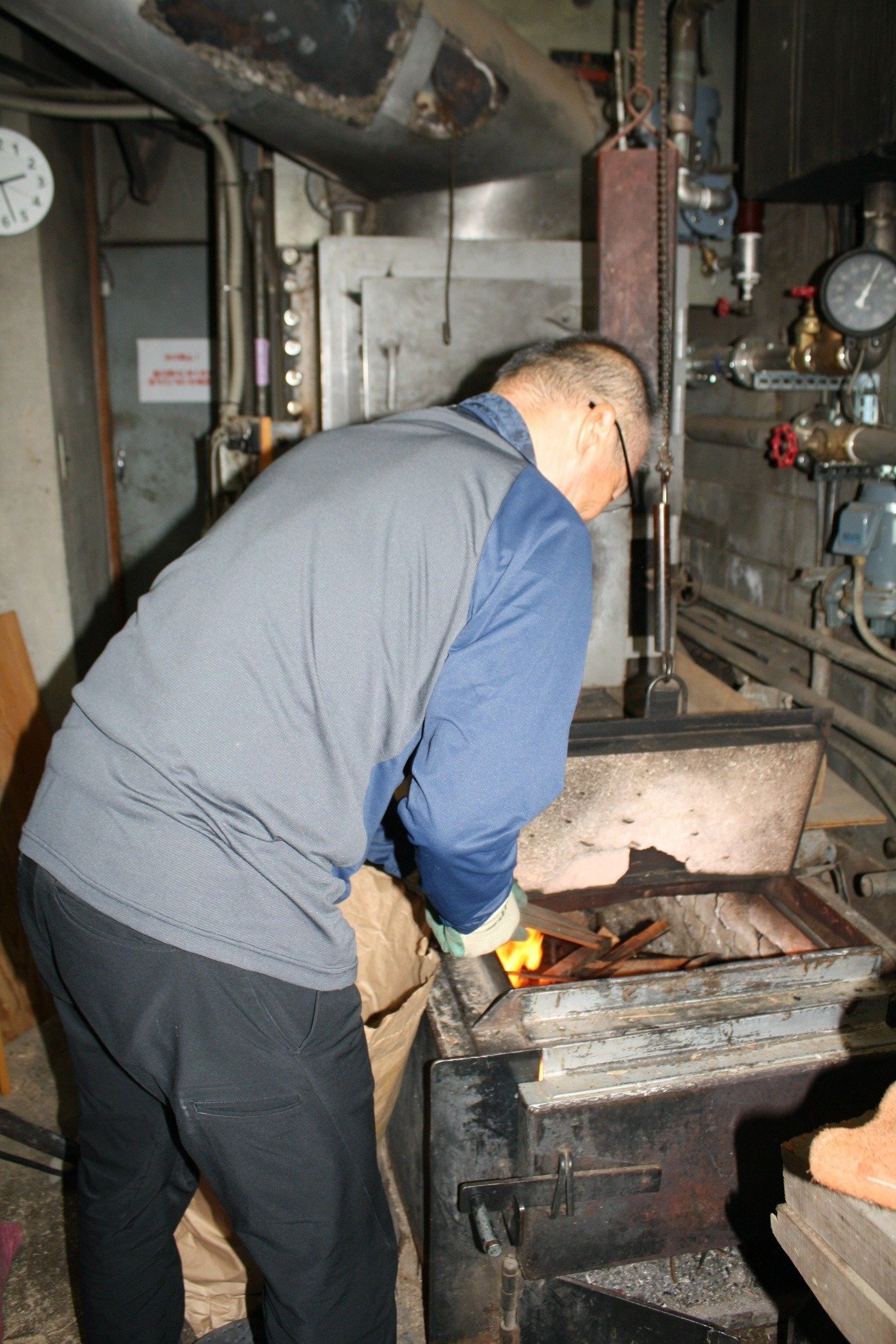 薪を投入して湯を沸かす間嶋さん