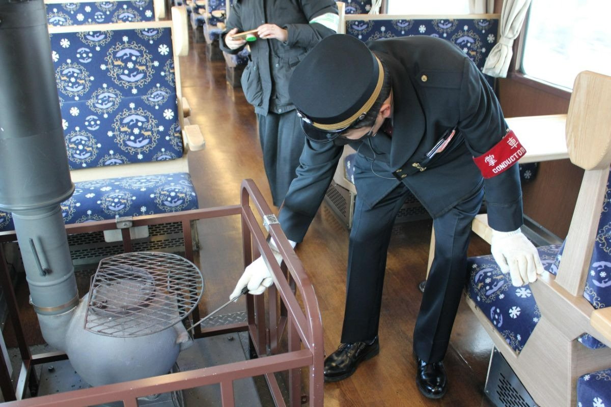 ダルマストーブに石炭をくべる車掌さん