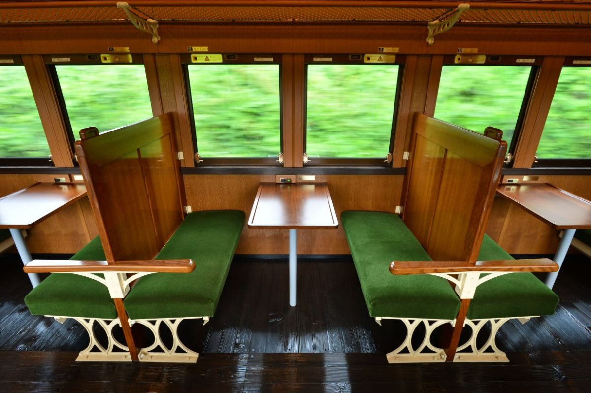座席のモケットが緑色、背もたれが木製のレトロな5号車