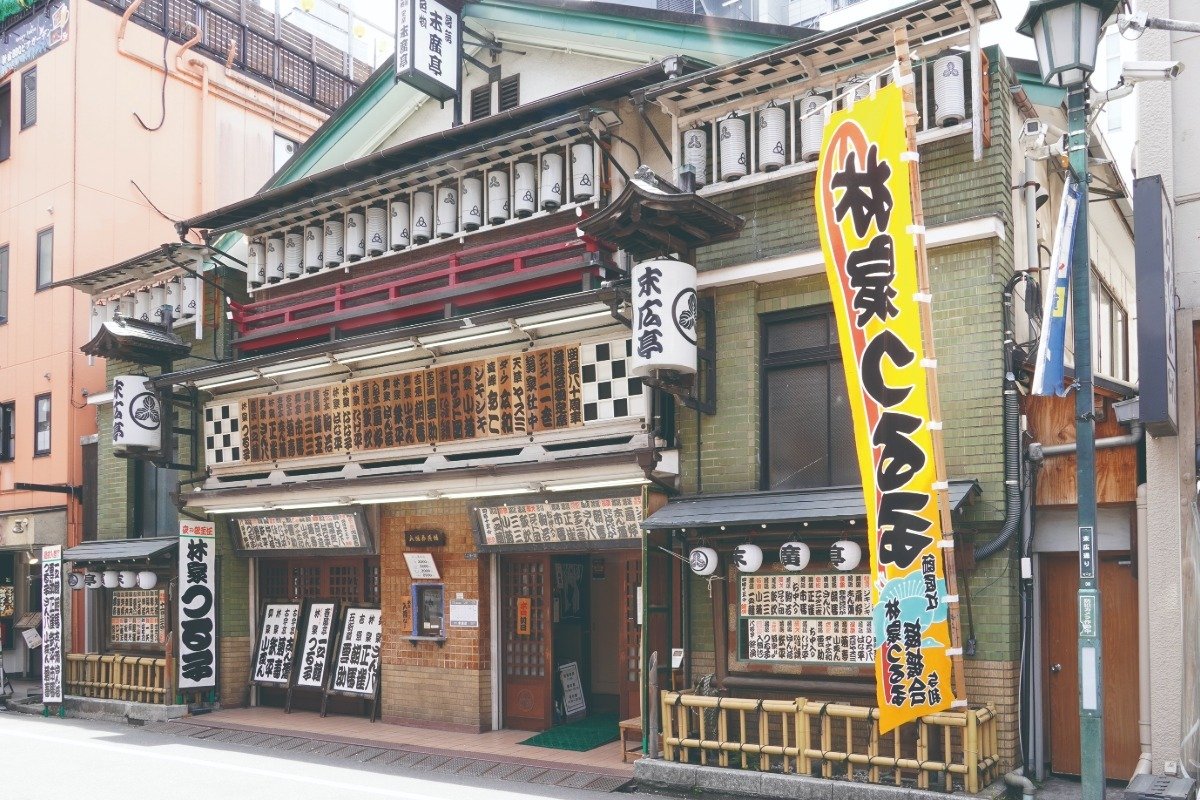 寄席文字で記された出演者名を確認し、窓口で料金を支払ってから中へ